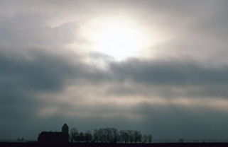 Photo Wolkenhimmel über einer Kirche mit kleinem Wald